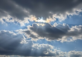 Obraz premium Sun rays shining through the clouds in the blue sky during daytime