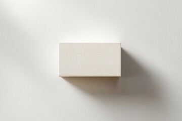 simple rectangular white block casting soft shadow on a plain white surface in minimalistic setting