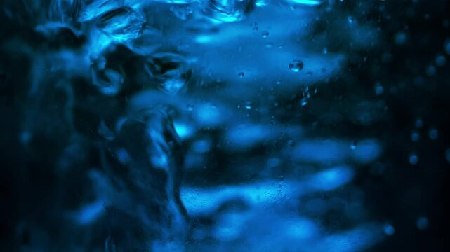 Boiling Water. Bubbles rising up on surface in blue-teal environment . Close Up.