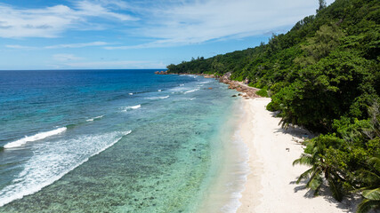 Fototapeta premium Transparent waters and white sand beach framed by tropical greenery. La Digue, Seychelles.