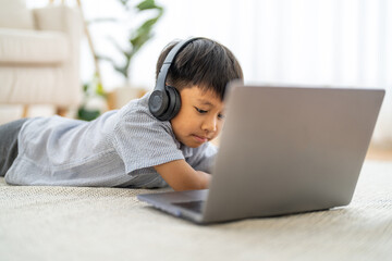 Asian boy using laptop with headphones course online learning, distance education for kids, e-learning at home, child studying digital technology, interactive education platform, remote class tutorial