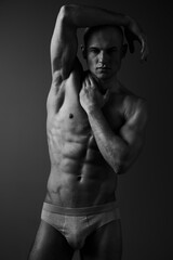 Naklejka premium Striking black and white portrait of a muscular man showcasing strength and confidence, perfect for fitness and wellness themes, capturing intense emotion effectively.