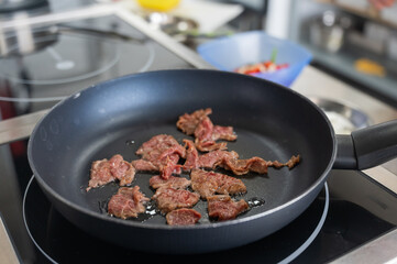 The chef fries veal in a frying pan. 