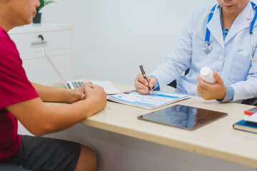 An experienced Asian male doctor consults with a male patient in a red shirt about men's health concerns. He explains a medical form, providing expert advice on urology and related health conditions