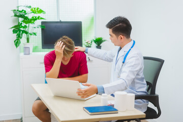 Fototapeta premium An experienced Asian male doctor consults with a male patient in a red shirt about men's health concerns. He explains a medical form, providing expert advice on urology and related health conditions