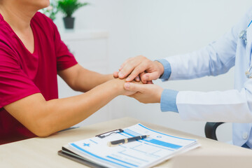 An experienced Asian male doctor consults with a male patient in a red shirt about men's health...