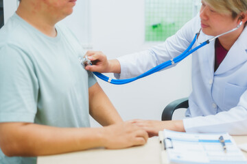 Asian male doctor specializing in cardiology explains heart disease to a patient using a heart...