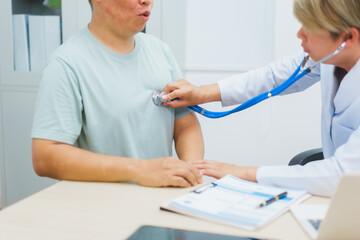 Asian male doctor specializing in cardiology explains heart disease to a patient using a heart...