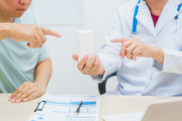 Asian male doctor specializing in cardiology explains heart disease to a patient using a heart...