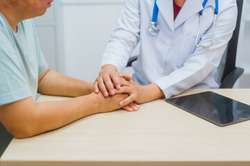 Asian male doctor specializing in cardiology explains heart disease to a patient using a heart...
