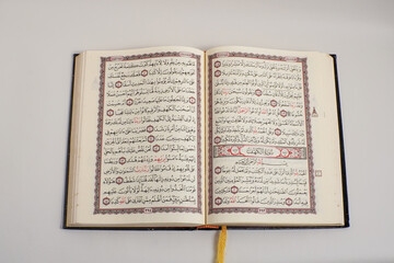 Obraz premium An open Quran showing Surah Al-Kahf with intricate Arabic calligraphy and elegant border design on a light background.