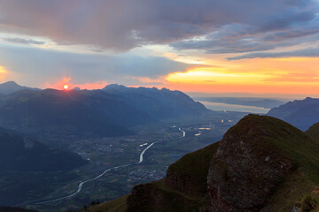 Mountain panorama with Rhone Valley, Lake Geneva and red sunset with burning sky and alpenglow in Swiss Alps, Switzerland