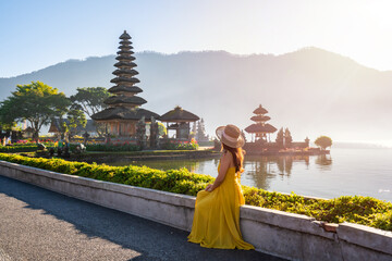 Young woman tourist relaxing and enjoying the beautiful view at Ulun Danu Beratan temple in Bali, Indonesia