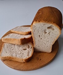 a loaf of bread sliced into plastics, the bread is fresh, delicious, on a cutting board