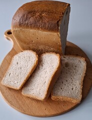 a loaf of bread sliced into plastics, the bread is fresh, delicious, on a cutting board