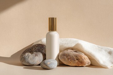 Cosmetic beauty product mockup bottle with rocks and wood, on a beige background with a white cloth.