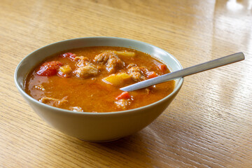 Bowl of Traditional Goulash Soup on Wooden Table – Hearty Meat, Peppers and Onion Stew.