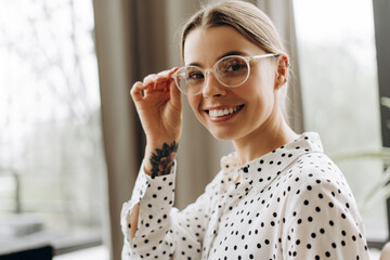 Smiling happy businesswoman adjusting glasses in modern office