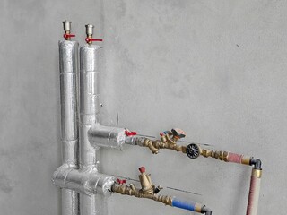 Industrial plumbing setup with insulated pipes and valves in construction environment