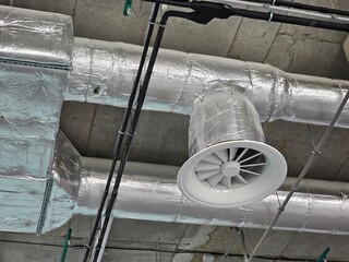 View of metallic ductwork ventilation system in modern industrial space with ceiling details