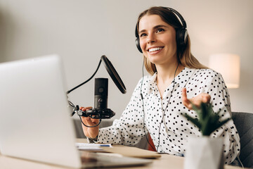 Happy female radio host recording podcast in home studio