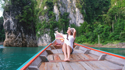 A woman sitting on a long tail boat while traveling on Cheow Lan Lake, Khao Sok, Surat Thani Thailand