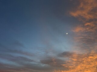 Fototapeta premium Abstract white and black clouds in a blue sky background image. Dramatic evening light and fiery orange sunset. 