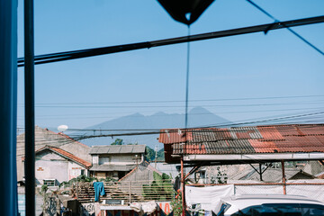 Naklejka premium Rustic rooftops against serene mountain backdrop under clear blue skies