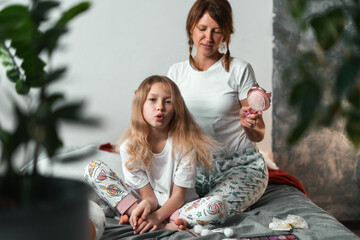 Morning hair care moment as mom combs daughters hair while smiling. Everyday life full of love,...