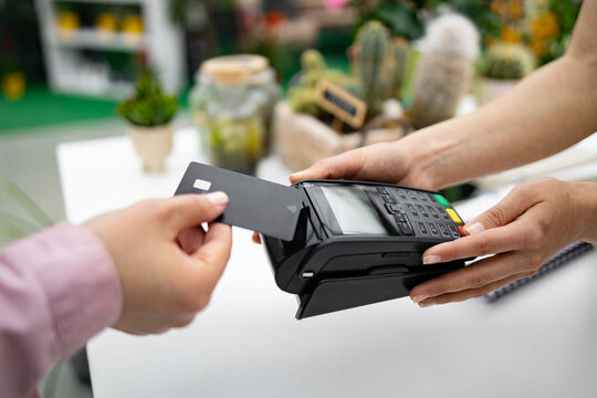 A person pays for purchases at a florist shop by using a credit card with a contactless payment terminal.