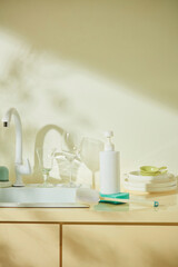 White spray bottles arranged near a sink under natural light. The image reflects a peaceful and clean kitchen setup. White pump bottle unlabeled for design, mockup for advertising