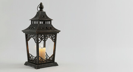 Decorative black lantern with a candle inside on a light background