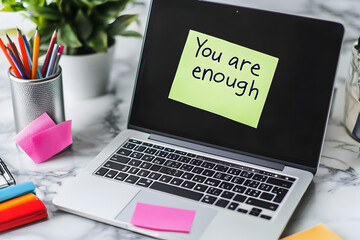Notes like "You are enough" or "Breathe" stuck on a laptop. Mental awareness theme