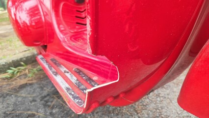 Displays a chipped or broken section on the lower edge of the scooter body near the footrest. The...