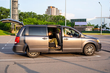 boy sits in a car on a hot day with the door and trunk open. Family day out
