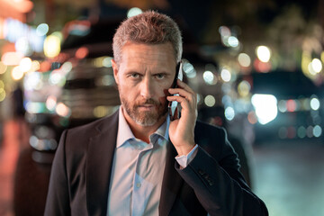 Businessman talk on phone at night city. Businessman in suit with phone in city. Businessman using...