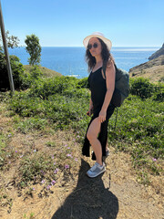 A girl in a hat walks by the sea