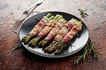 Grilled green asparagus with bacon on a brown vintage background.