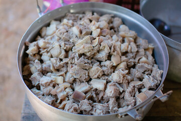 Pork bones are chopped into pieces in a large pot.