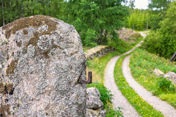 Hinge on a boulder as a gatepost by an old dirt road with stone walls in the countryside