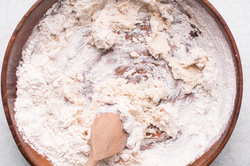 Overhead view of bread dough being mixed in a wooden bowl, top view of homemade bread dough in a mixing bowl, process of making artisan bread