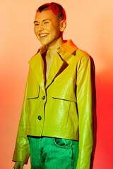 young woman smiling brightly in green textured jacket and blue jeans, colorful warm background, joyful mood, modern casual style fashion portrait