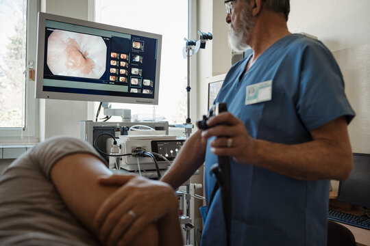 Doctor looking at monitior during gastroscopy procedure, examining upper digestive tract.