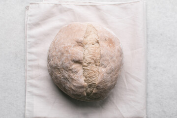 Overhead view of homemade artisan bread on a white countertop, top view of baked sourdough artisan bread on a white background