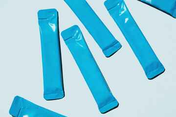 Blue Foil Sachets are Scattered on Light Blue Background. Packaging for Single Serving Products. Food and Beverage Industry.