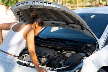 Young cuban woman checking engine of broken car on roadside