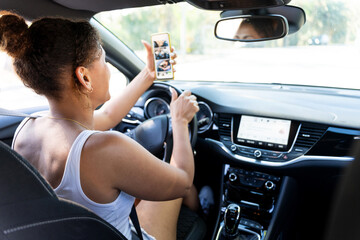 Woman driving car looking at smartphone photos and not paying attention to road