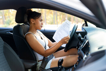 Young cuban woman reading documents while driving a car