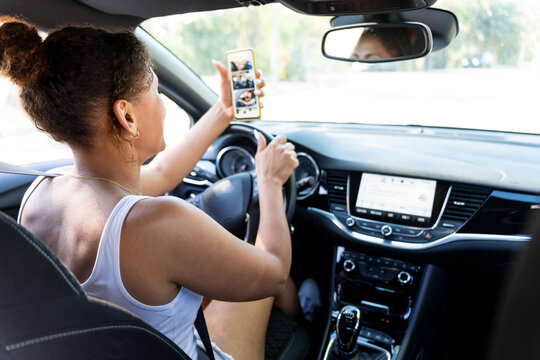 Woman driving car looking at smartphone photos and not paying attention to road