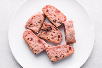 Overhead view of strawberry and chocolate sourdough on a white plate, top view of pink and chocolate artisan bread on a white background, open crumb artisan bread on white background